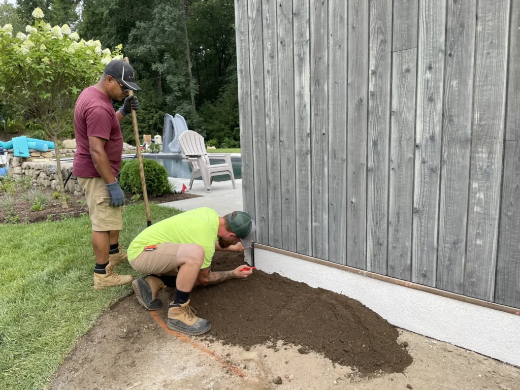 Two contractors working around a building foundation